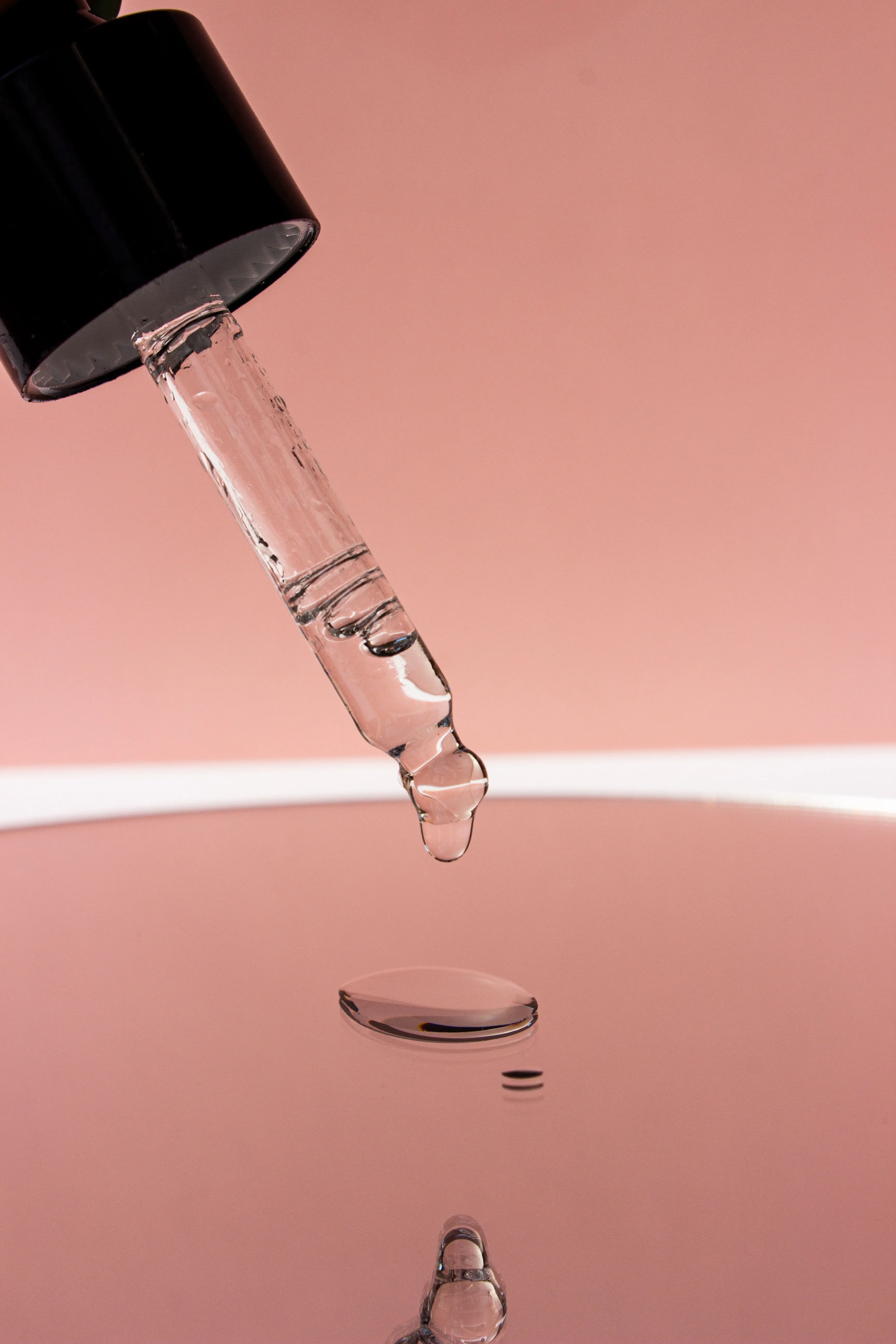 Brightening serum for glass skin — dropper close up pink background