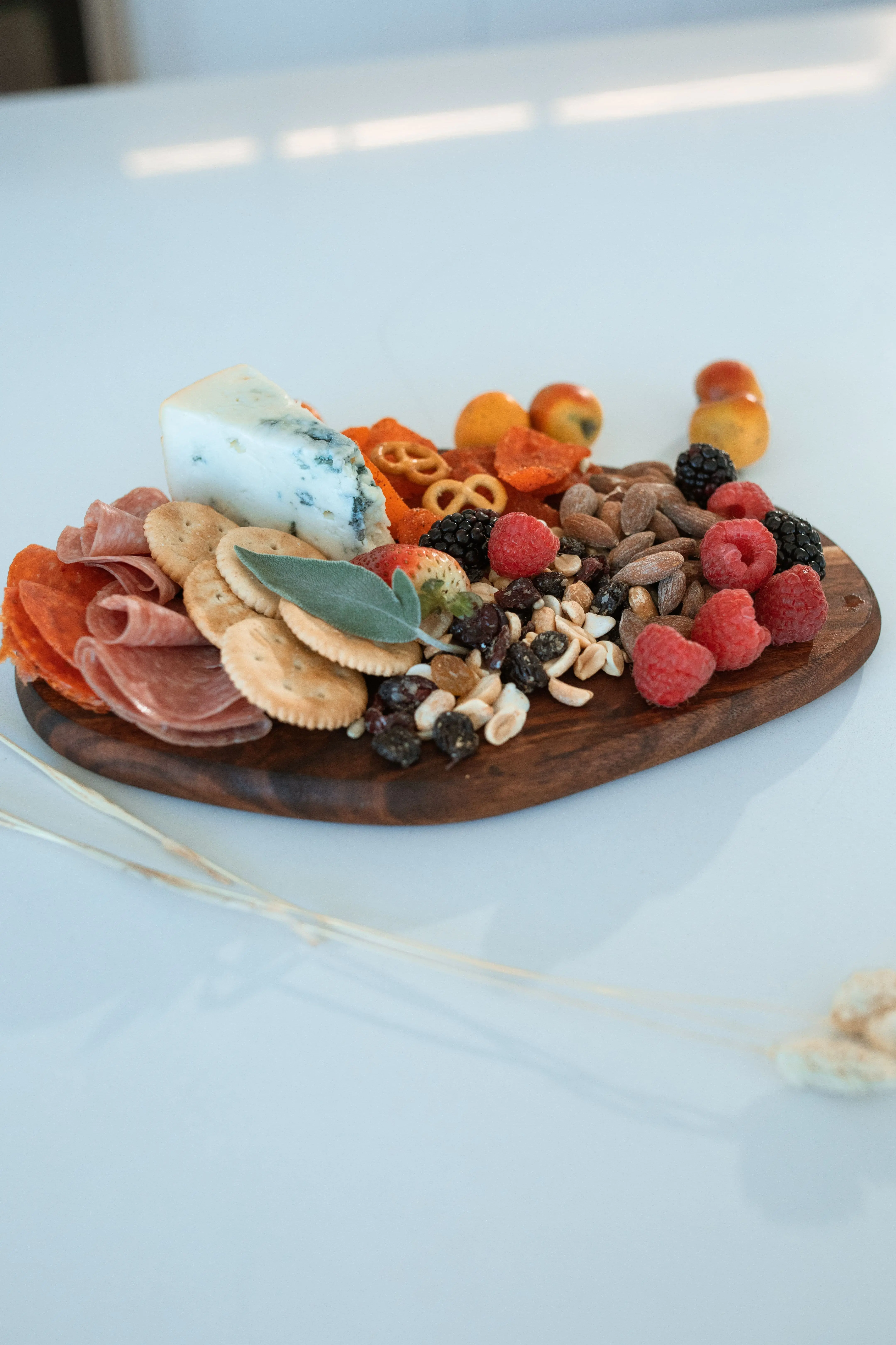 Easy grazing board with blue cheese, prosciutto, crackers and mixed berries on a wooden oval board