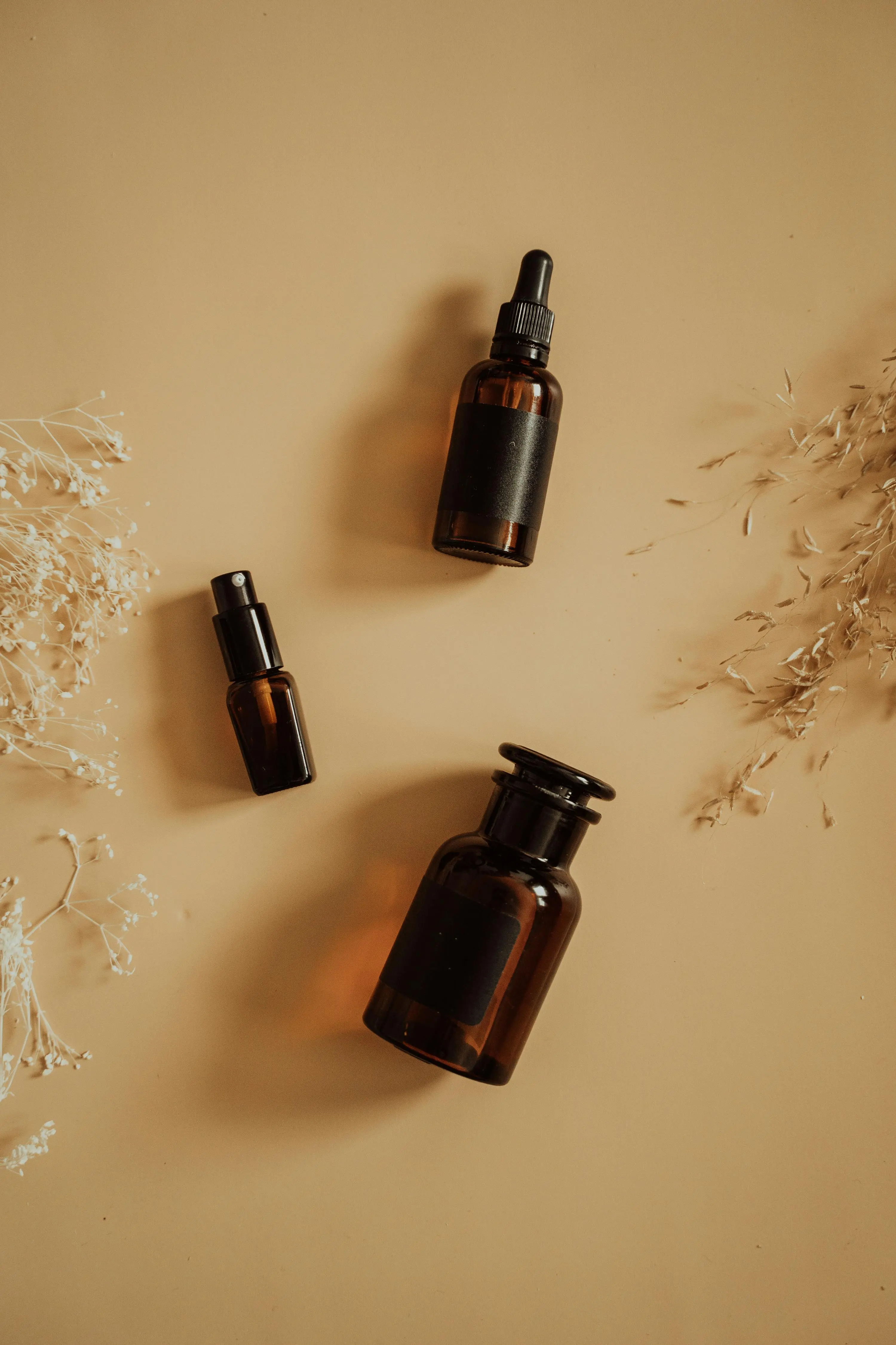 Glass skin ingredients — amber serum bottles flatlay on warm ochre background with dried botanicals