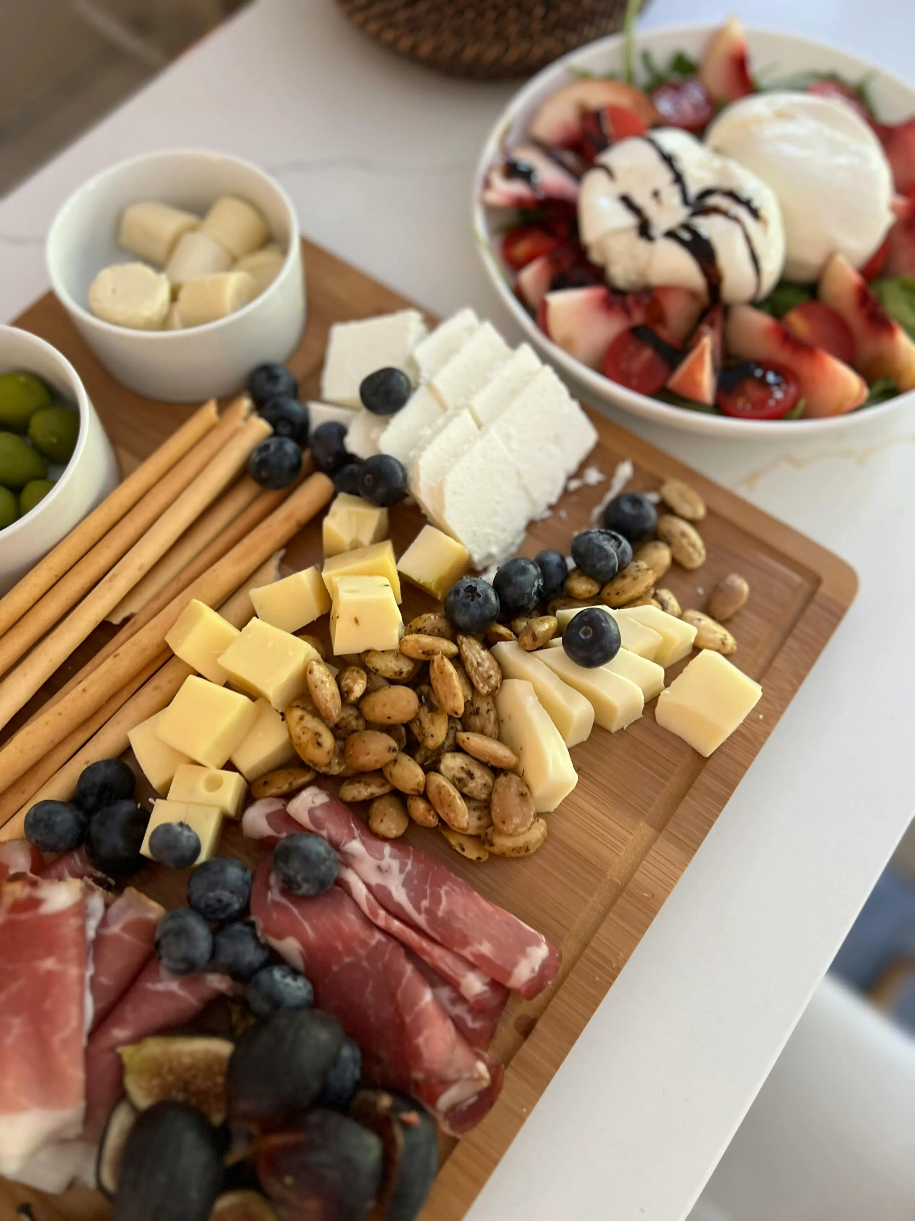 Grazing board with prosciutto, blueberries, cheese cubes, olives and breadsticks