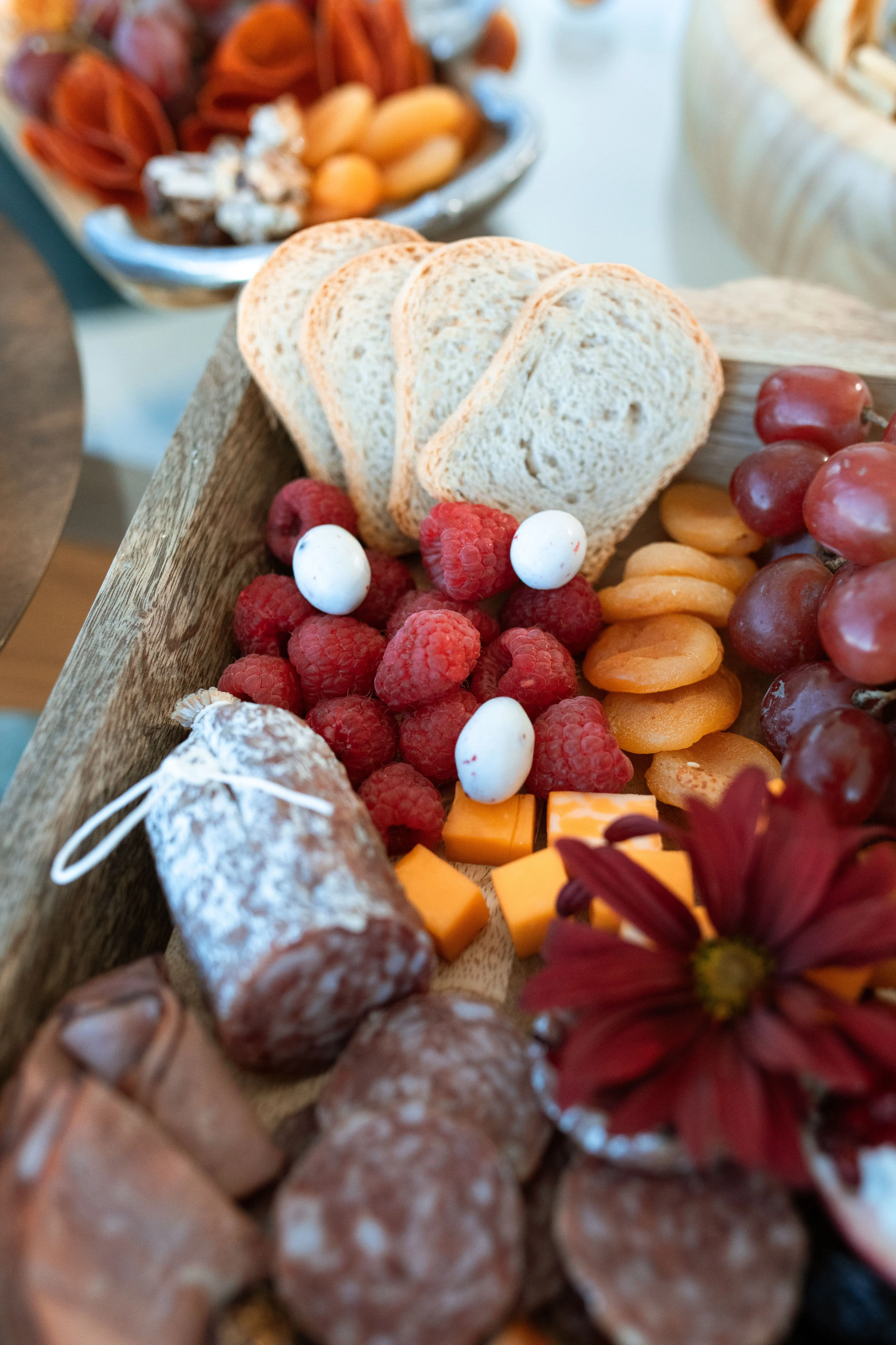 Rustic grazing board with salami, raspberries, bread slices and flowers for a party