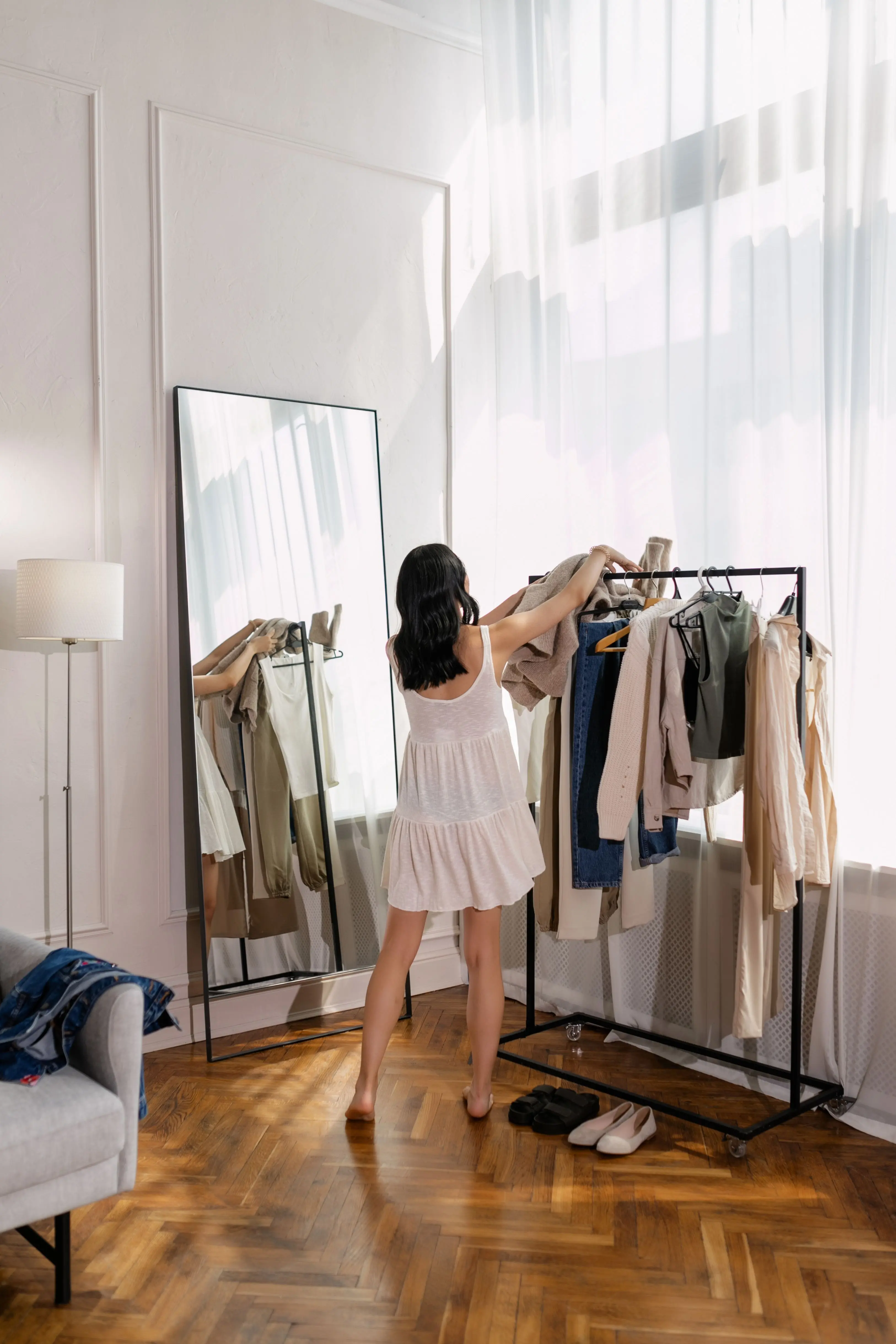 How to build a capsule wardrobe step by step — woman organizing clothes on a clothing rack