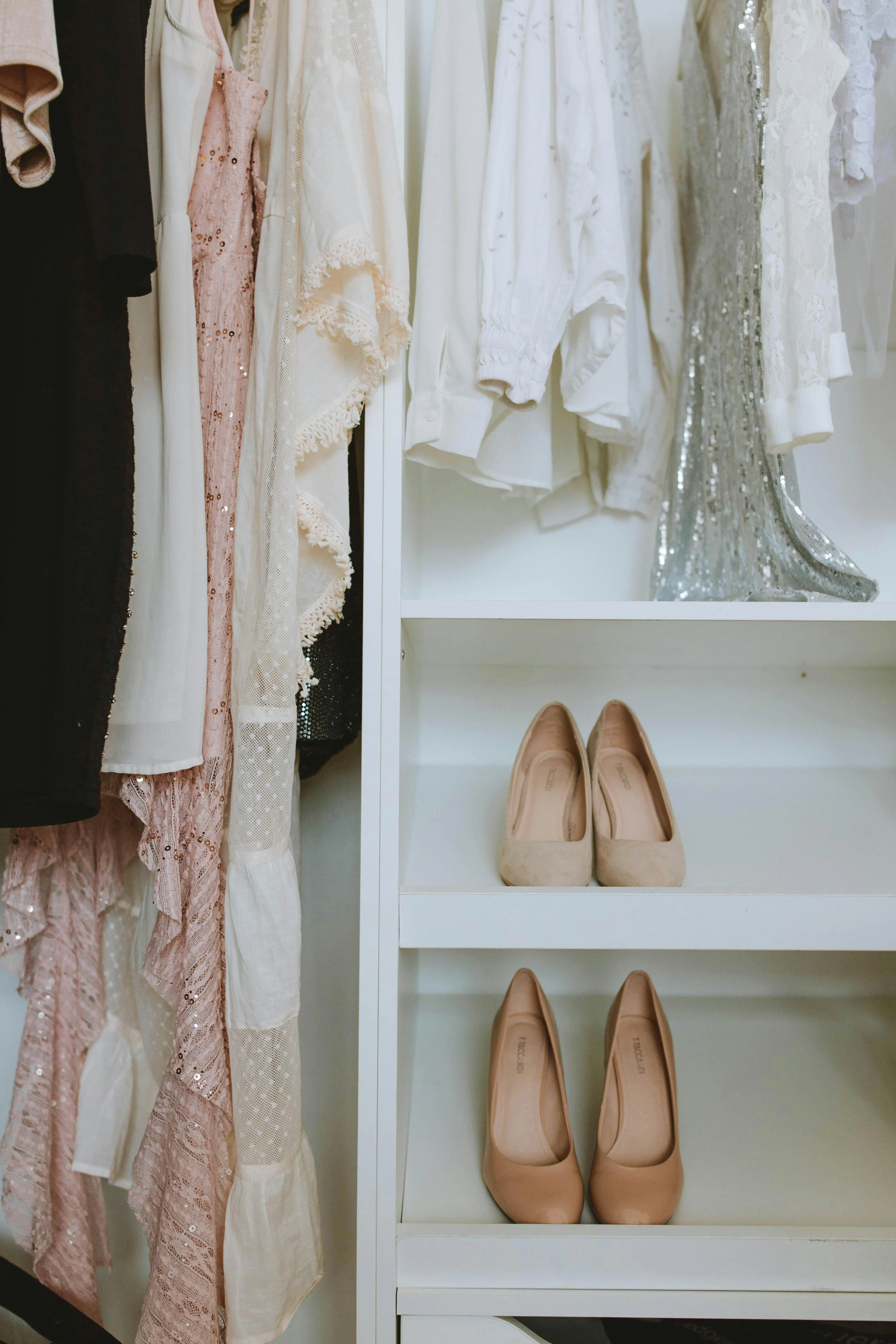 What is a capsule wardrobe — earth tone clothes on a white rack with dried botanicals